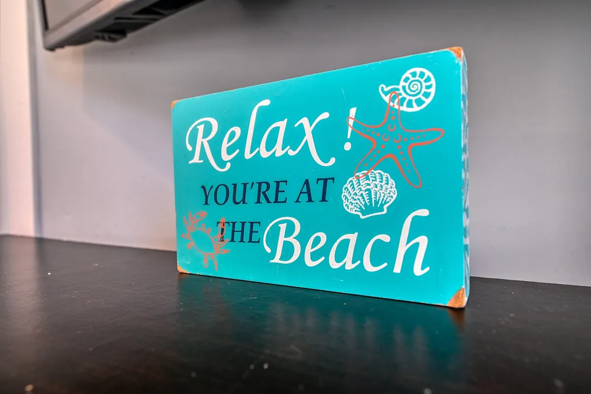 This image features a decorative sign with colorful text and beach-themed graphics, set in a casual, cheerful environment that evokes the welcoming spirit of island life. The atmosphere suggests a space where guests gather to share stories or plan their next outing, connecting the interior with the broader beach community.
