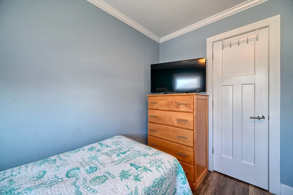 A comfortable bedroom with a bed adorned in a patterned quilt, a wooden dresser, and a television set, all designed to foster relaxation and quiet evenings.