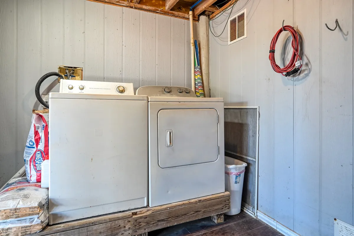 A close-up interior view of a washer and dryer set, along with laundry supplies organized on shelves nearby. The space is clean, practical, and functional, designed for easy access to shared laundry amenities.